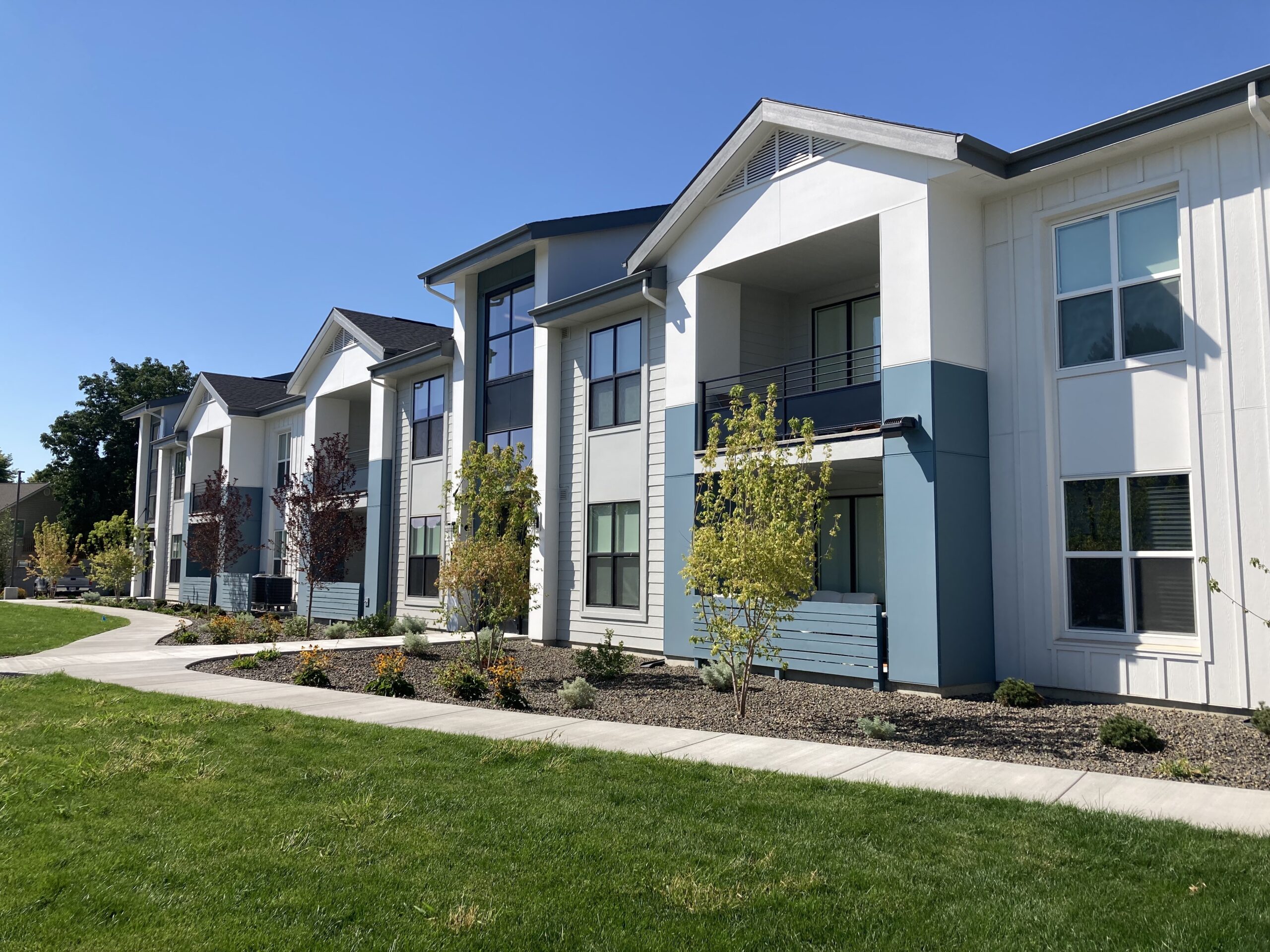 Two-story apartments with sidewalk and lawn.