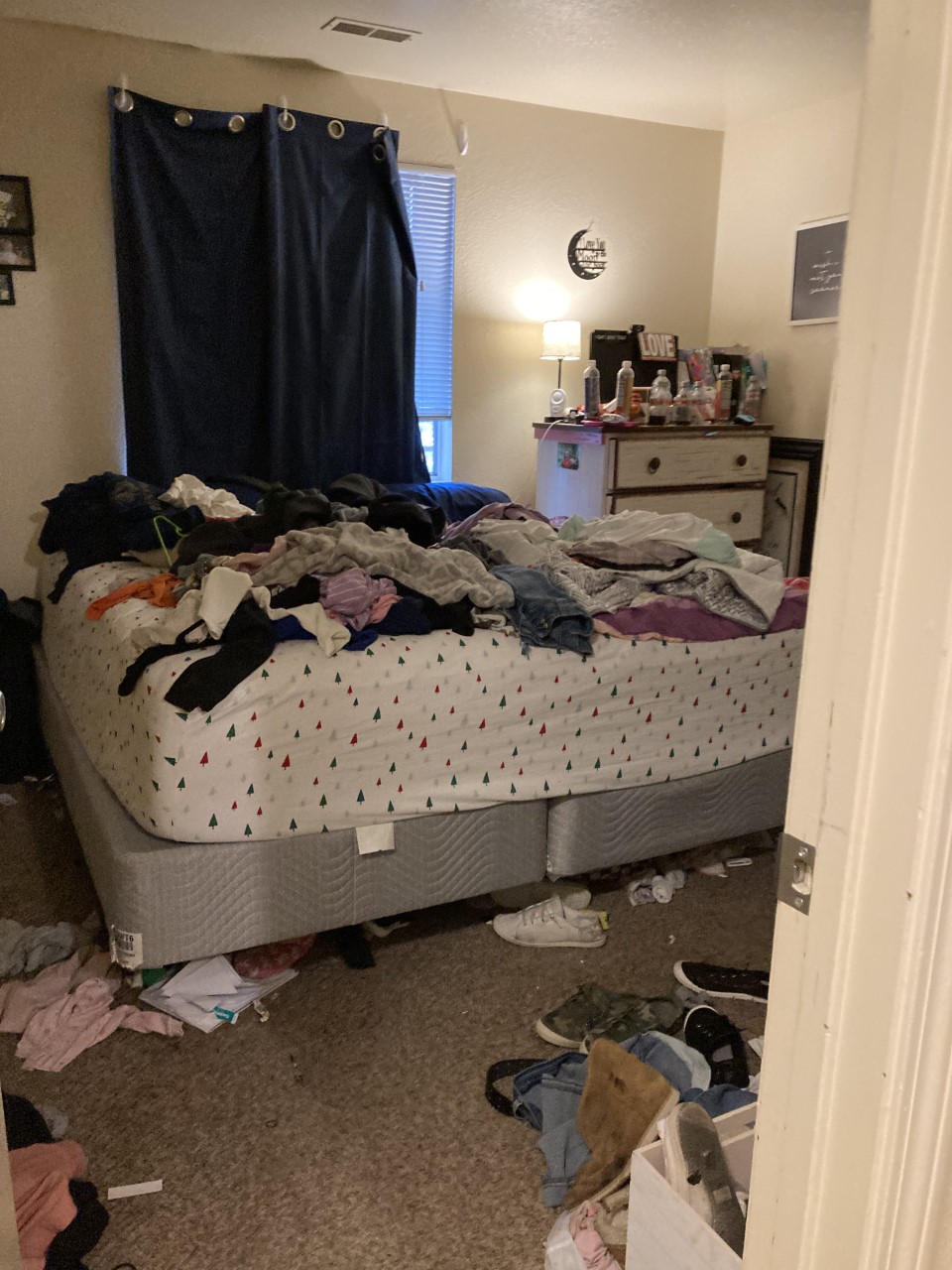 Messy bedroom with clothes and trash strewn around the floor.